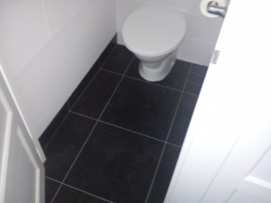 Here the vinyl tiles have been cut to to accomadate the toilet and siliconed for a water tight seal to ensure hygene.